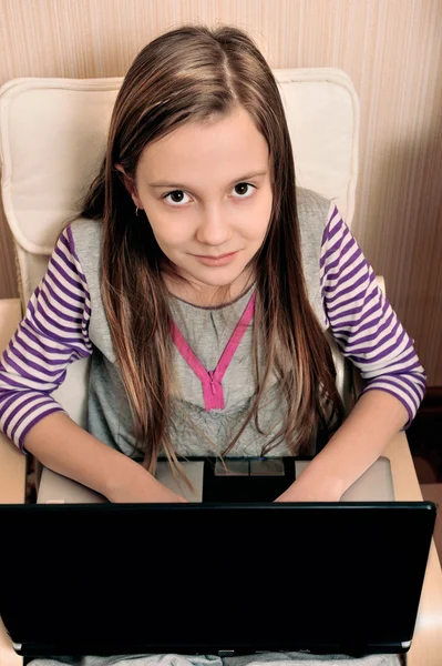 肘掛け椅子に座っているラップトップで彼女の仕事をやっている若い女の子 — ストック写真