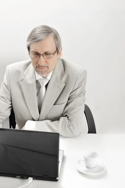 Porträtt av en äldre affärsman med en dator och en kopp. — Stockfoto