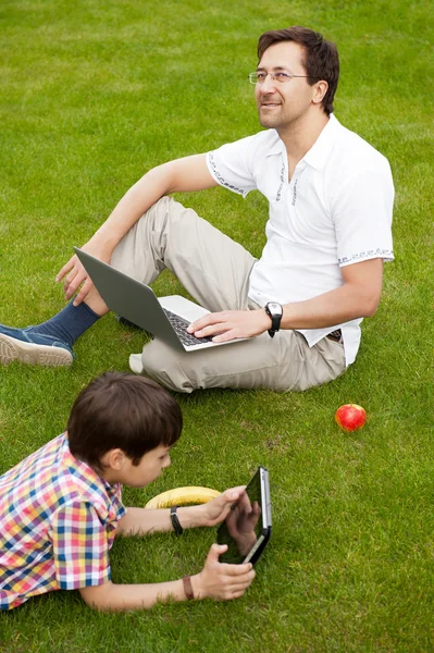 Man and young boy his son sitting outdoors — Stock Photo, Image
