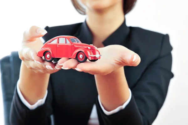 Portrait of young handsome woman holding car in her arms — Stock Photo, Image