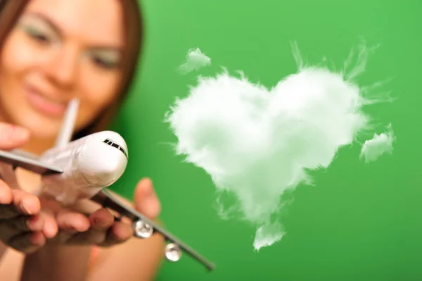 Hübsche junge Frau spielt mit Plastikflugzeug auf grünem Backgr — Stockfoto