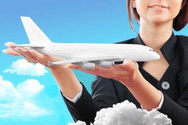 Portrait of young happy woman stewardess holding jet aircraft in clipart