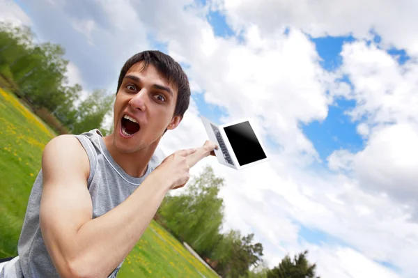 Glad ung man med en laptop utomhus — Stockfoto