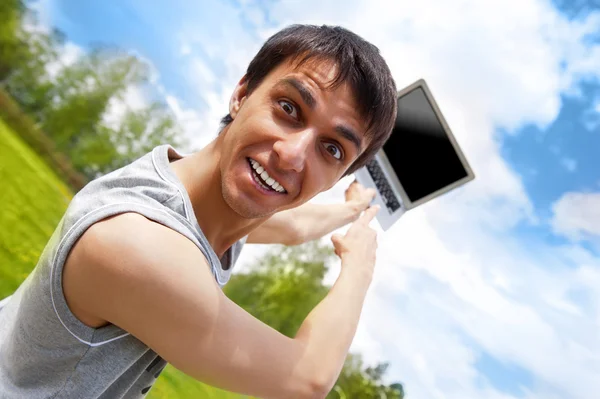 Щасливий молодий чоловік з ноутбуком на відкритому повітрі — стокове фото