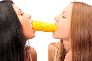 Two women eating corn at the same time from different sides clipart