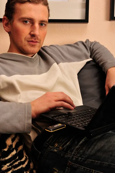 Šťastný mladý muž sedí na gauči doma — Stock fotografie