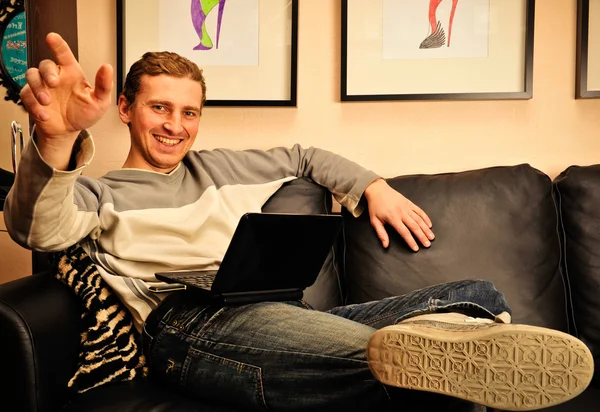 Счастливый молодой человек сидит дома на диване — стоковое фото