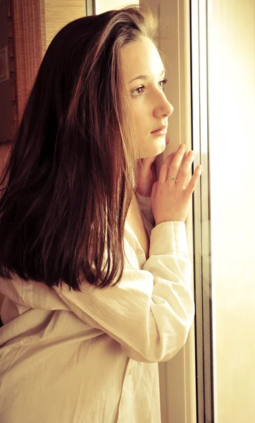 Porträtt av mysiga ung flicka står nära ett fönster hemma — Stockfoto