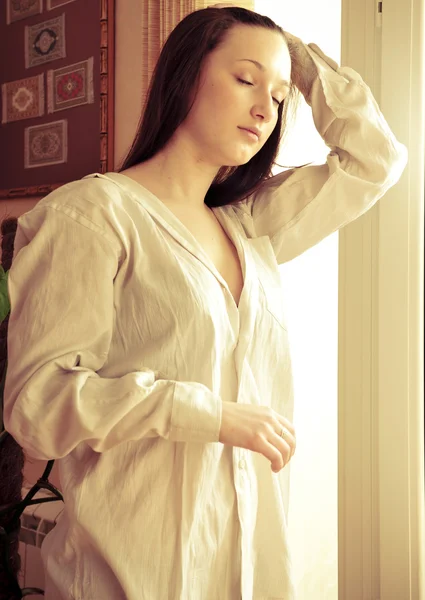 창의 집에서 가까이 서 있는 아늑한 젊은 여자의 초상화 — 스톡 사진