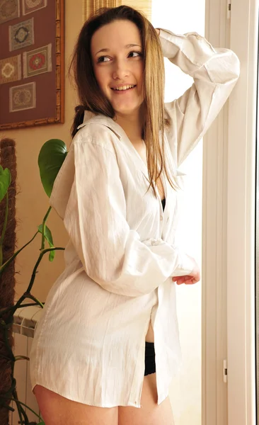 Πορτρέτο του φιλόξενο νεαρό κορίτσι στέκεται κοντά σε ένα παράθυρο στο σπίτι — Φωτογραφία Αρχείου
