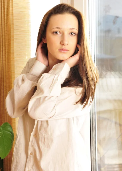 Retrato de menina acolhedora de pé perto de uma janela em casa — Fotografia de Stock