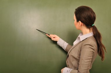Portrait of young woman teacher standing near blackboard and exp clipart