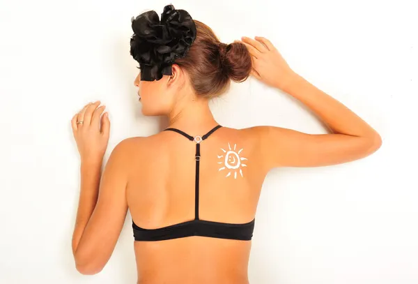 Loción protector solar sobre piel de mujer bronceada hecha como forma de sol —  Fotos de Stock