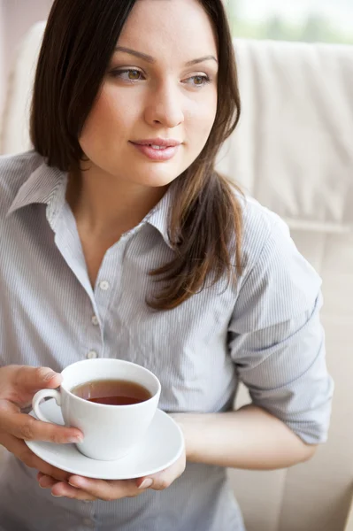 Mujer joven en casa bebiendo té de una taza — Foto de Stock