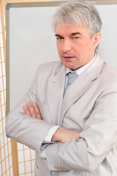 Closeup of a mature smiling business man standing in a light at — Stock Photo, Image