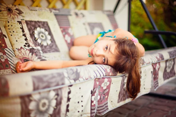 Artistic lifestyle photo of little girl leaning on swing sofa ou — Stock Photo, Image