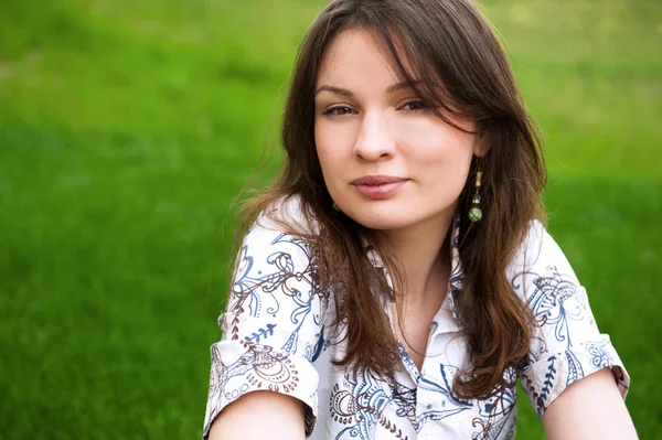 Retrato de cerca de una mujer joven y bonita descansando sobre hierba y sonrisas —  Fotos de Stock