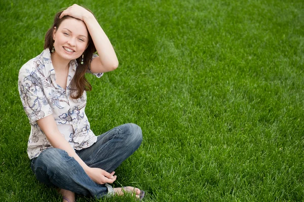 Volle Länge der hübschen jungen Frau, die auf Gras ruht und lächelt — Stockfoto