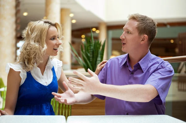 Young debating or talking couple inside mall sitting near the ta — Stock Photo, Image