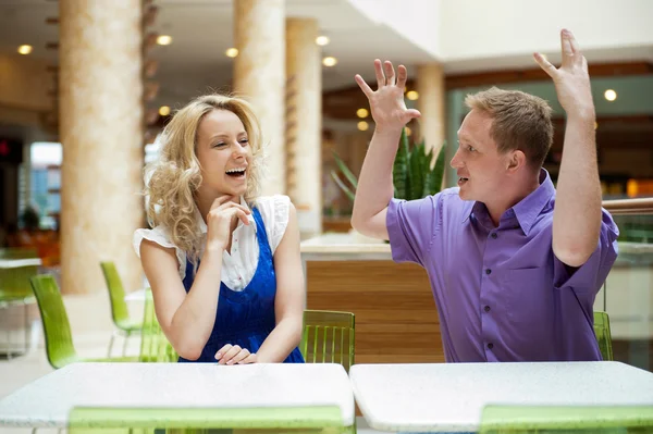Jóvenes debatiendo o hablando pareja dentro del centro comercial sentado cerca de la ta —  Fotos de Stock