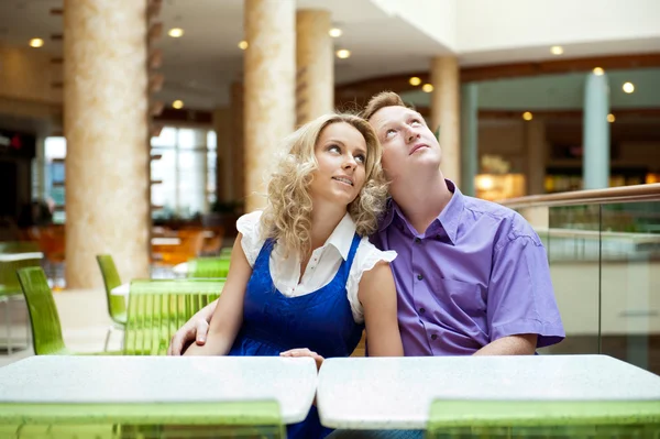 Retrato de um jovem casal feliz olhando para longe enquanto sentado perto — Fotografia de Stock