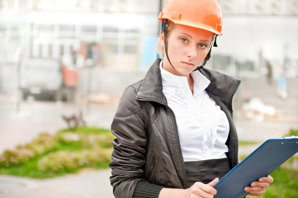 Young architect-woman wearing a protective helmet standing on th — Stock Photo, Image