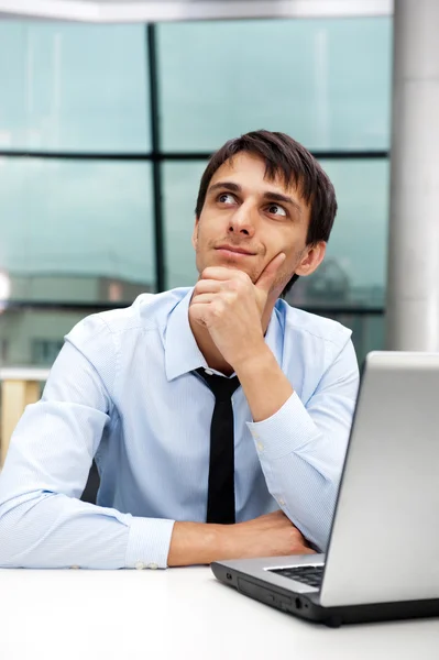 Porträtt av en ung affärsman som sitter med sin laptop i den av — Stockfoto