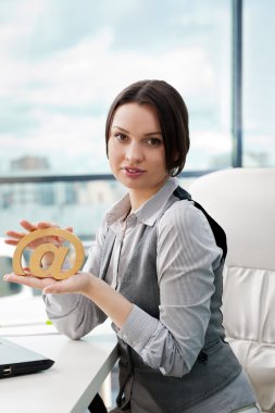 Portrait of a cheerful Business woman sitting on her desk holdin clipart