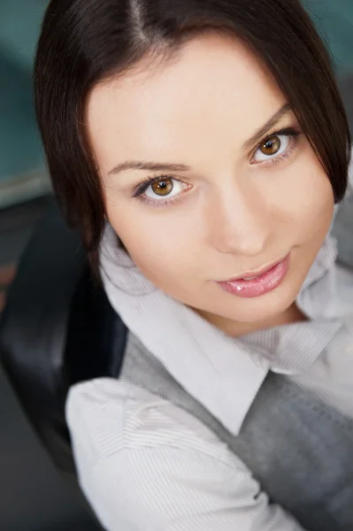 Porträtt av ung affärskvinna som sitter vid hennes skrivbord med ett smil — Stockfoto