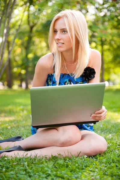 Όμορφη δασκάλα γυναίκα με ένα φορητό υπολογιστή που κάθεται στο πράσινο γρασίδι στο — Φωτογραφία Αρχείου