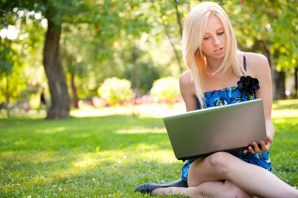 Beautiful student woman with a laptop sitting on green grass at — Stock Photo, Image