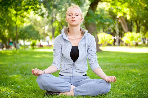 Porträtt av ung kvinna mediterar i pose Lotus på gröna gra — Stockfoto
