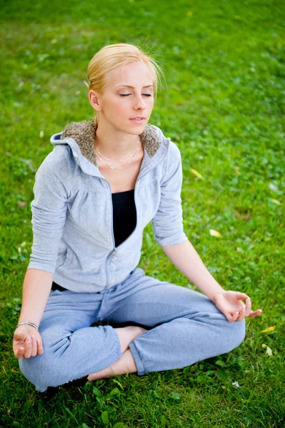 Retrato de mulher jovem meditando em pose de lótus em gra verde — Fotografia de Stock