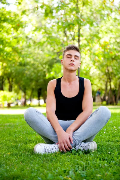Piękny młody człowiek w pozie medytacji na zewnątrz. — Zdjęcie stockowe