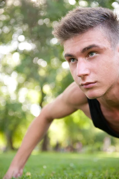 Portrét mladého muže, plný přístup dělat kliky na trávě na — Stock fotografie