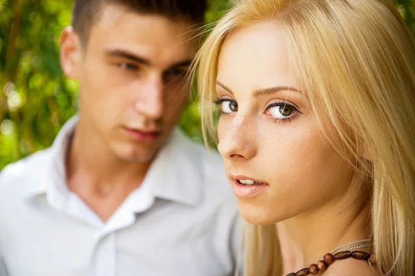 Portrait of beautiful young couple standing against green tree i — Stock Photo, Image