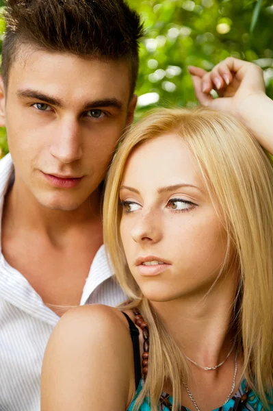 Portrait of beautiful young couple standing against green tree i — Stock Photo, Image