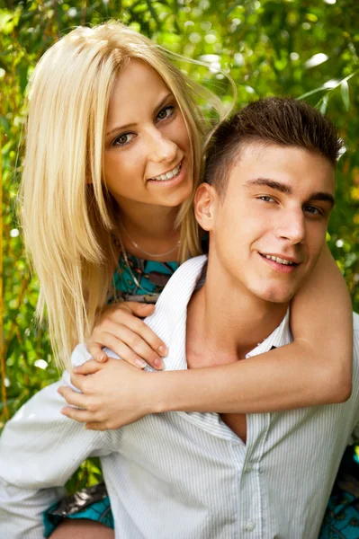 Young couple playing around in the nature - front view. Against — Stock Photo, Image