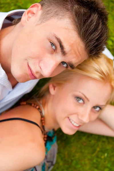 Szczęśliwa para młodych, leżąc na trawie — Zdjęcie stockowe