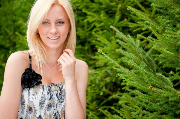 Retrato de uma jovem mulher sexy sorrindo em um parque contra o abeto tr — Fotografia de Stock