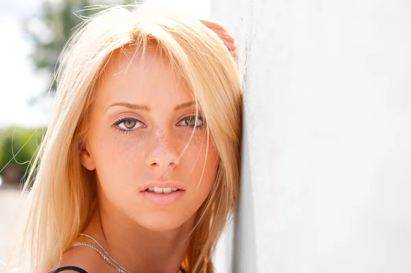 Portret van vrij jonge vrouw permanent buiten in de buurt van witte muur — Stockfoto