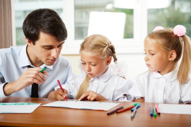 Teacher helping students with schoolwork in school classroom. Ho