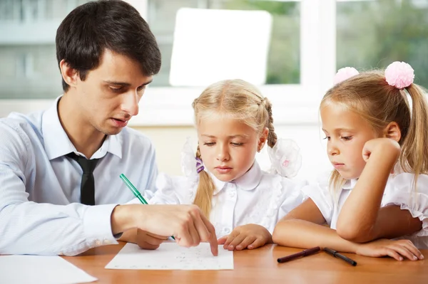 Teacher helping elementary school pupils with their tasks — Stock Photo, Image
