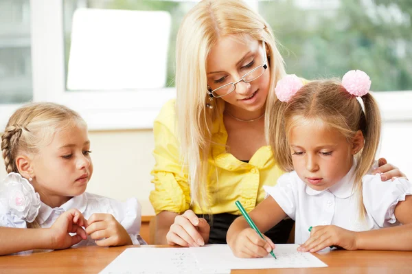 Lehrerin hilft kleinen Mädchen, eine Übung im Klassenzimmer zu machen — Stockfoto