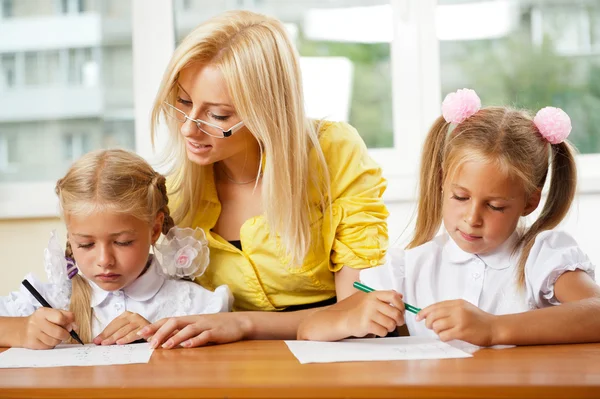 Lehrerin hilft kleinen Mädchen, eine Übung im Klassenzimmer zu machen — Stockfoto