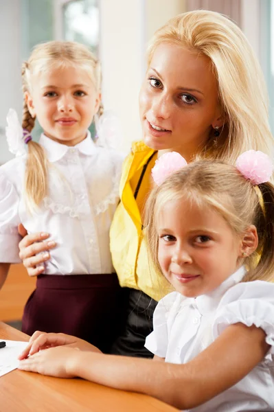 Junge hübsche Lehrerin hilft ihren kleinen Schülern im Klassenzimmer — Stockfoto