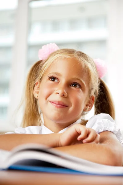 Portret van een jong meisje op school aan de balie. — Stockfoto