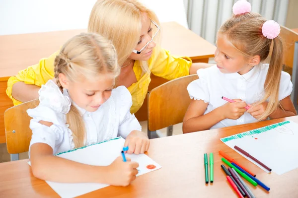 Young pretty teacher helping to her students to make exercise in — Stock Photo, Image