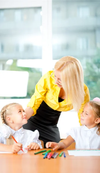 Young pretty teacher helping to her students to make exercise in — Stock Photo, Image