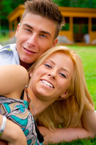 Portrait of beautiful young couple sitting on ground in park rel — Stock Photo, Image